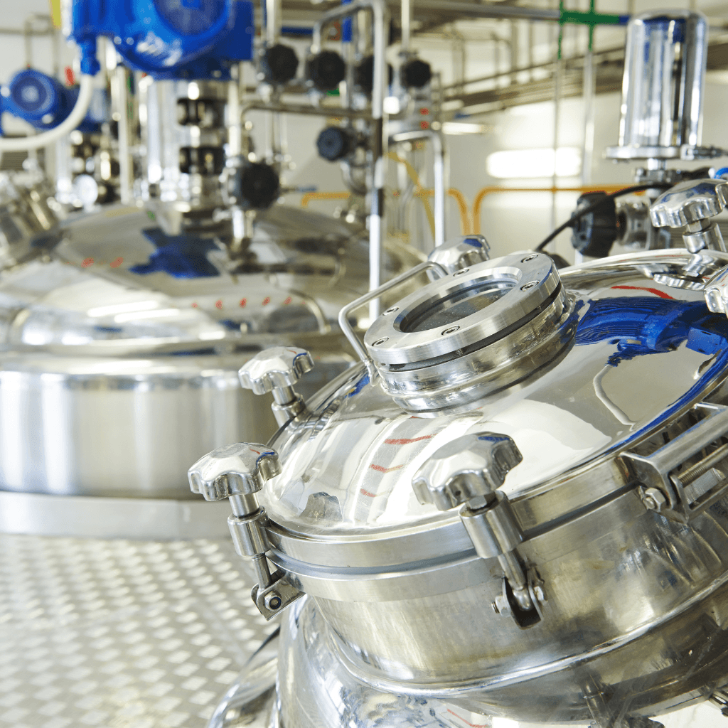 Stainless steel reactor vessel with manhole and piping in industrial processing plant