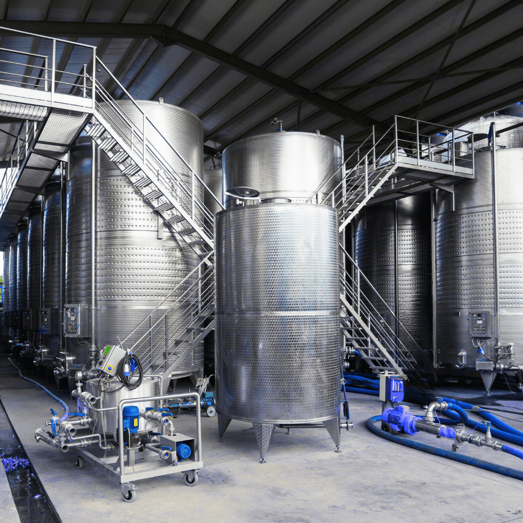 Stainless steel storage tanks with piping system and access platform in industrial plant